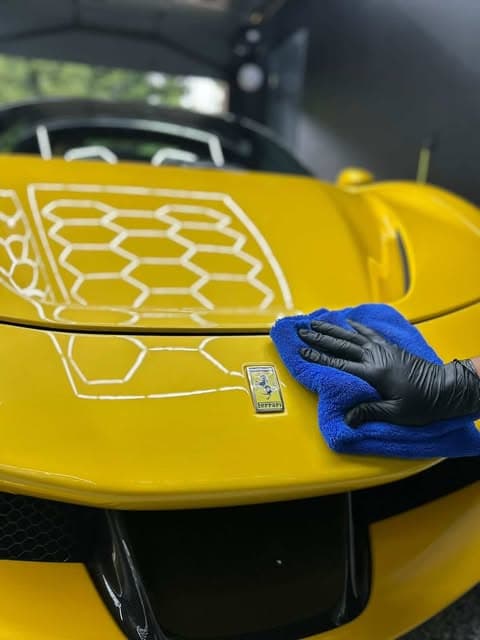 Yellow Ferrari being hand-finished after a ceramic coating by Gold Grade